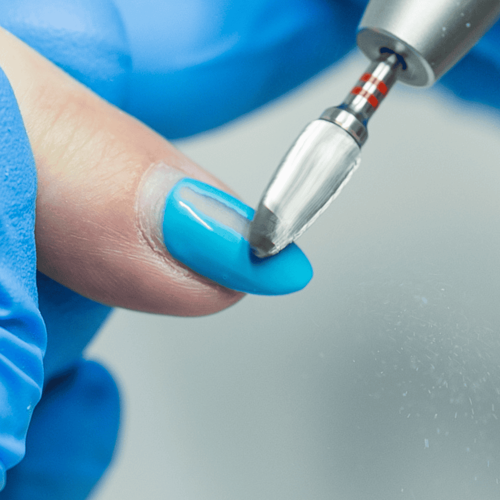 Efile nail bit being used on a finger to remove blue gel polish 